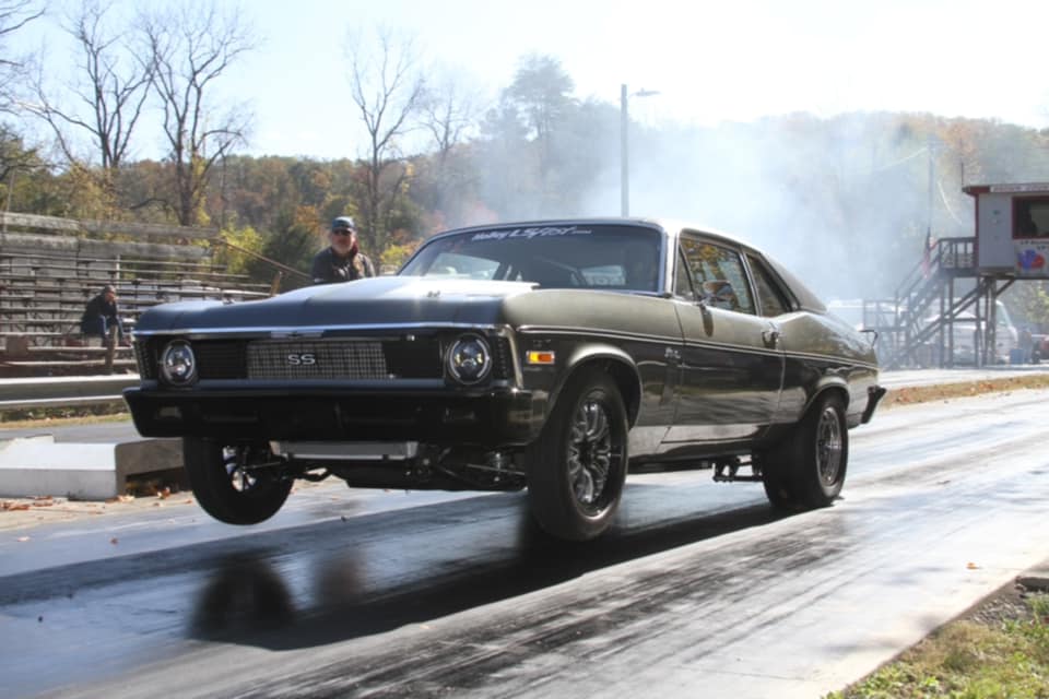 Black muscle car on a racetrack with smoke in the background